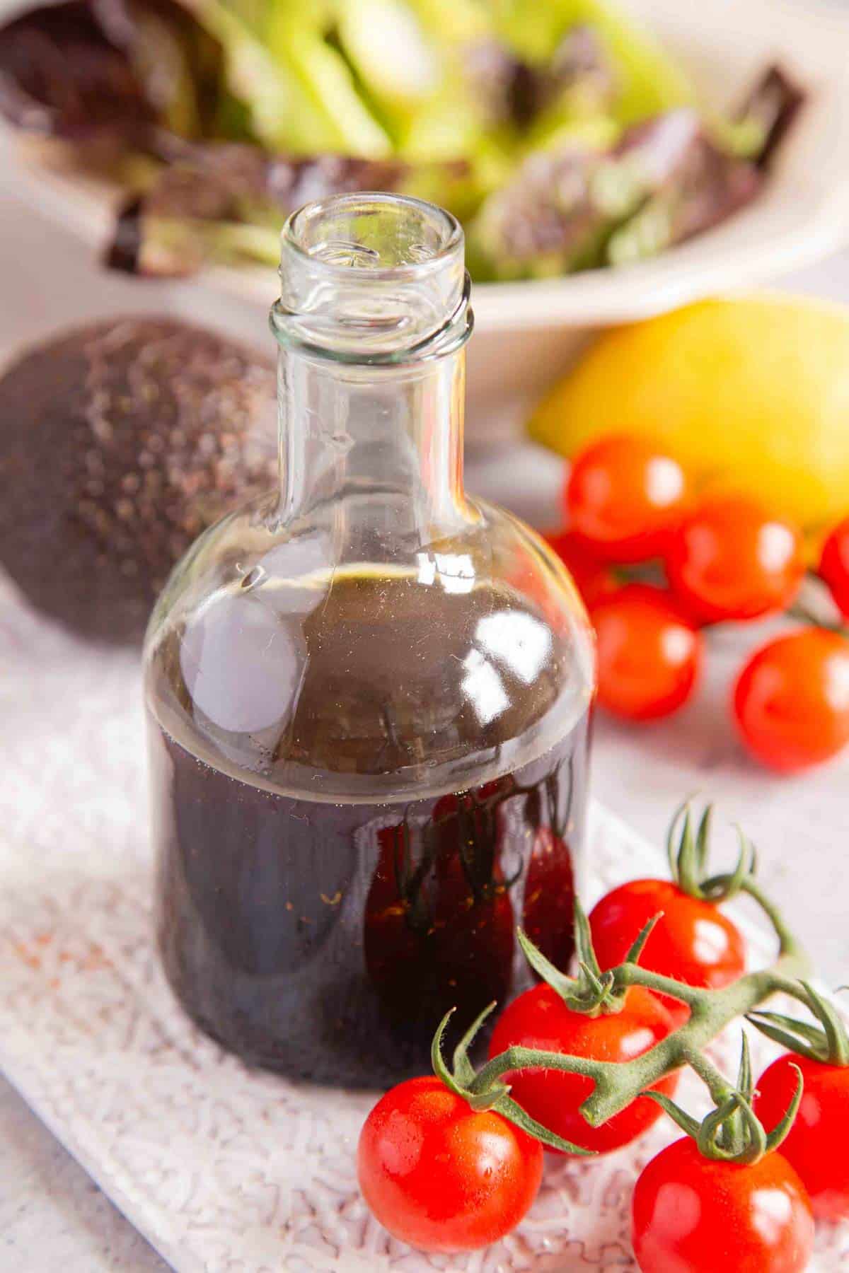 a pretty glass bottle of the finished dressing surrounded with fresh vine tomatoes, a lemon and avocado
