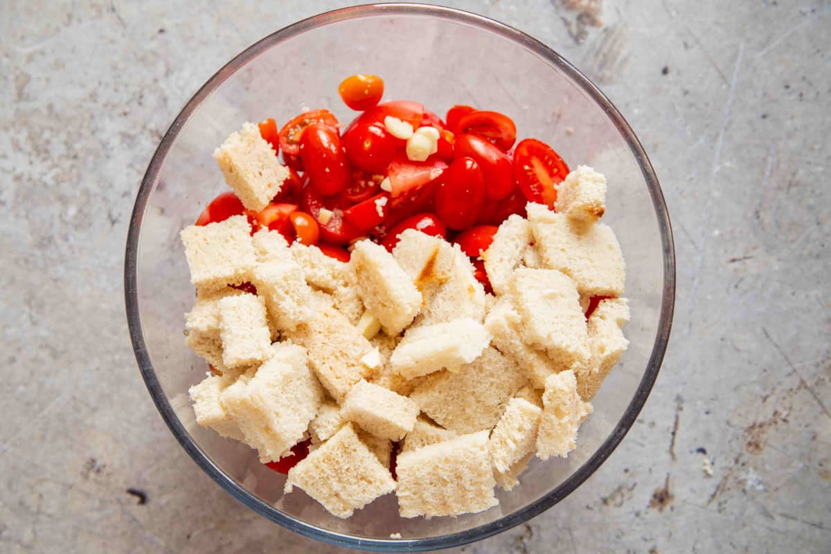 chopped tomatoes, bread, garlic and water in a bowl ready to be blended
