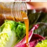 a close up of pouring the dark caramel coloured dressing onto red and green salad leaves
