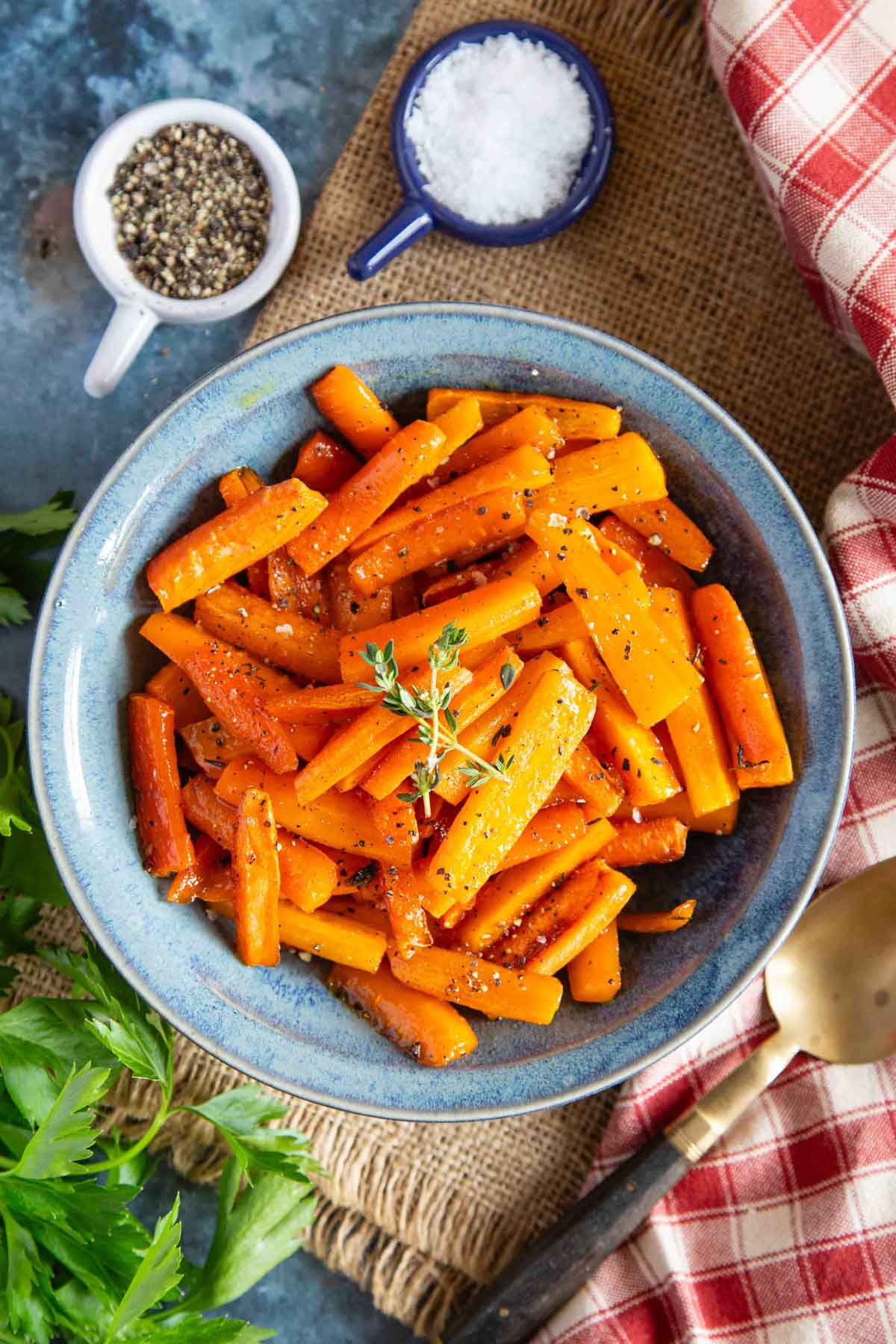 a top down image of a table set with a blue bowl of freshly made honey roasted carrots