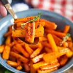 a table set with a blue bowl of freshly made honey roasted carrots