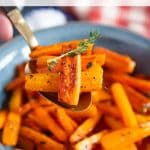 a spoon of honey roasted carrots being lifted from a blue serving bowl