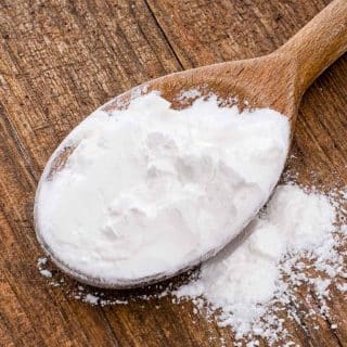 a wooden spoon of white cornflour on a wood table