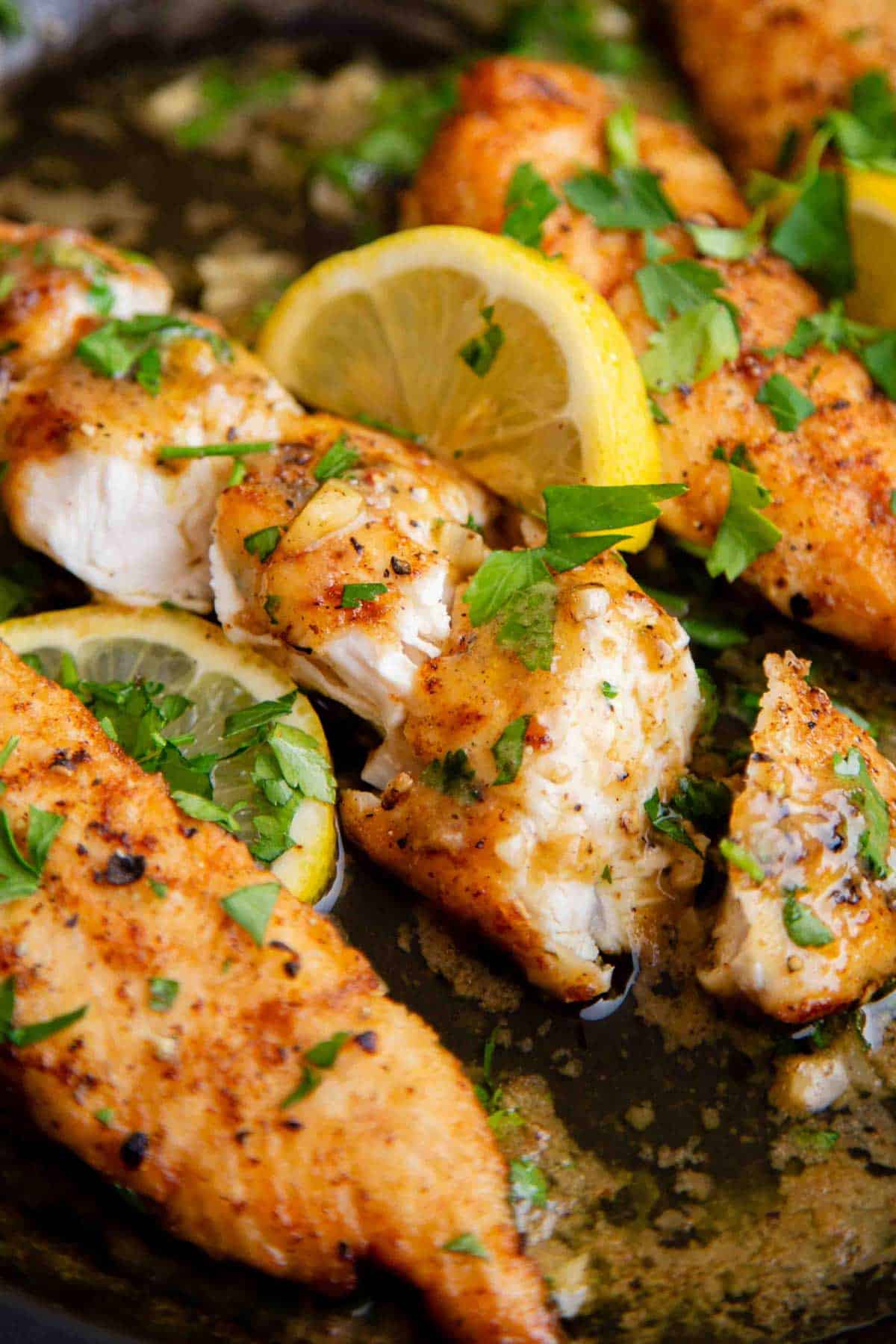 sliced garlic chicken garnished with a slice of lemon and parsley
