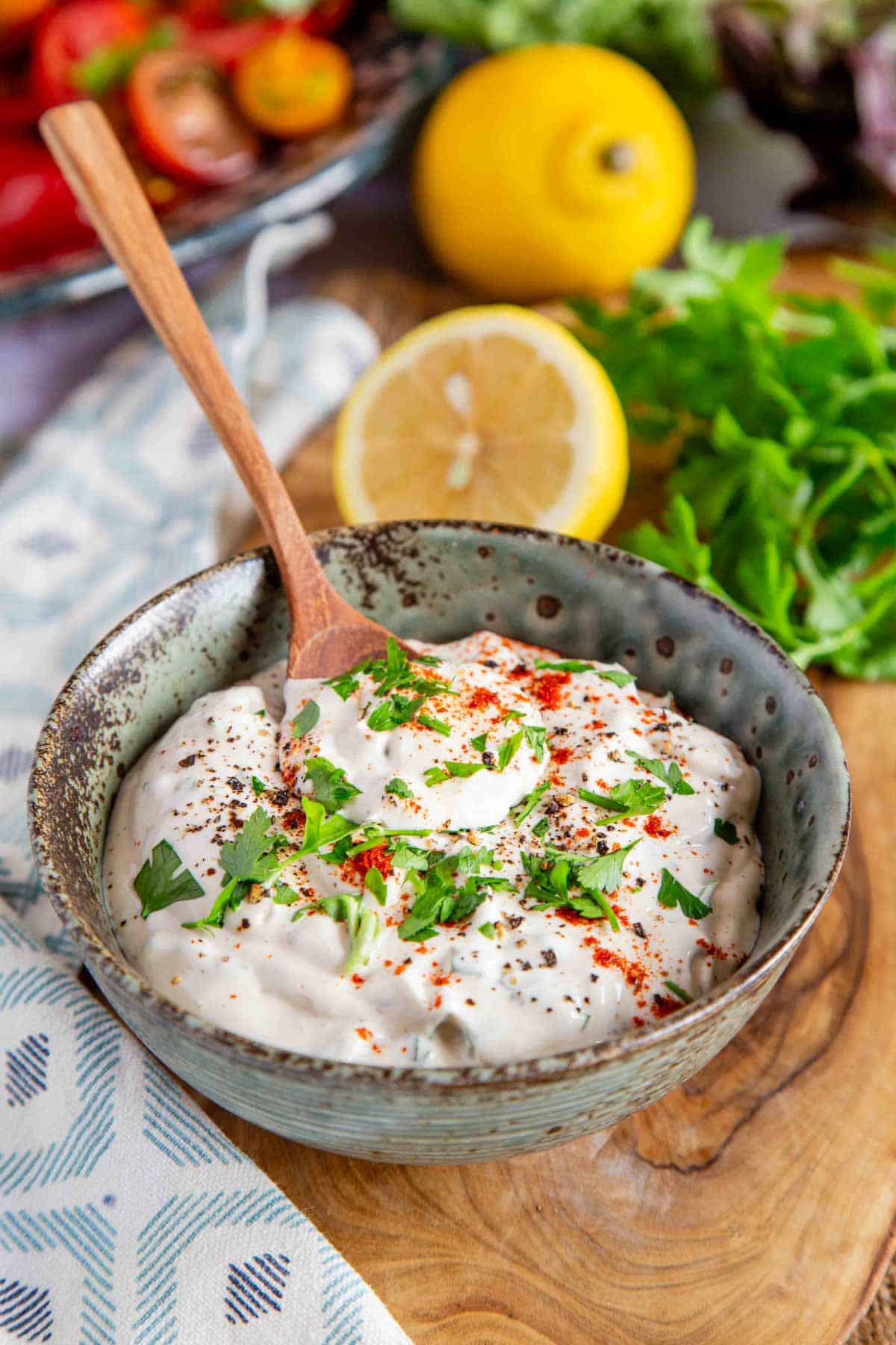 a bowl of creamy white shawarma sauce garnished with chopped parsley