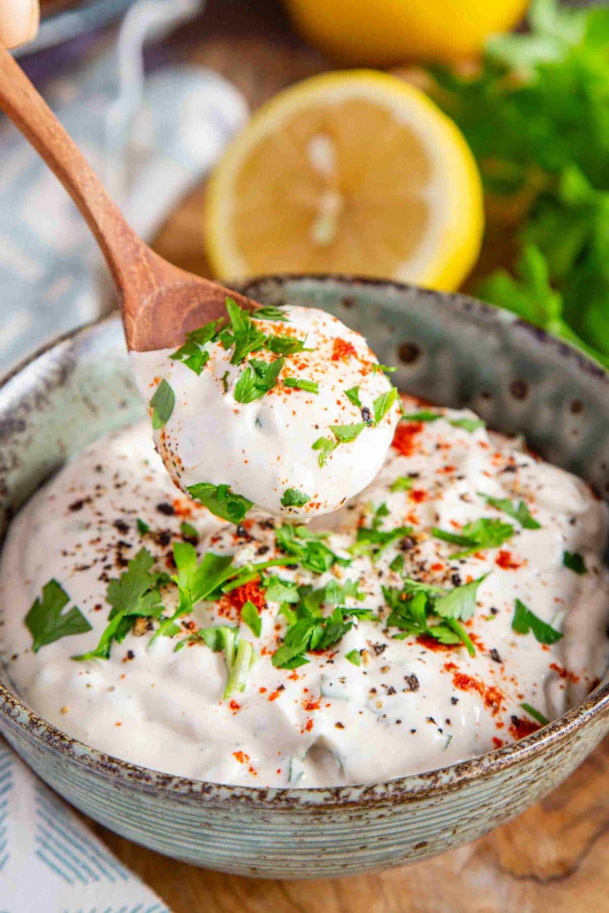 a bowl of creamy white shawarma sauce garnished with chopped parsley