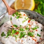 a bowl of creamy white shawarma sauce garnished with chopped parsley