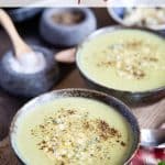 two bowls of pale green broccoli and stilton soup garnished with crumbled stilton and black pepper