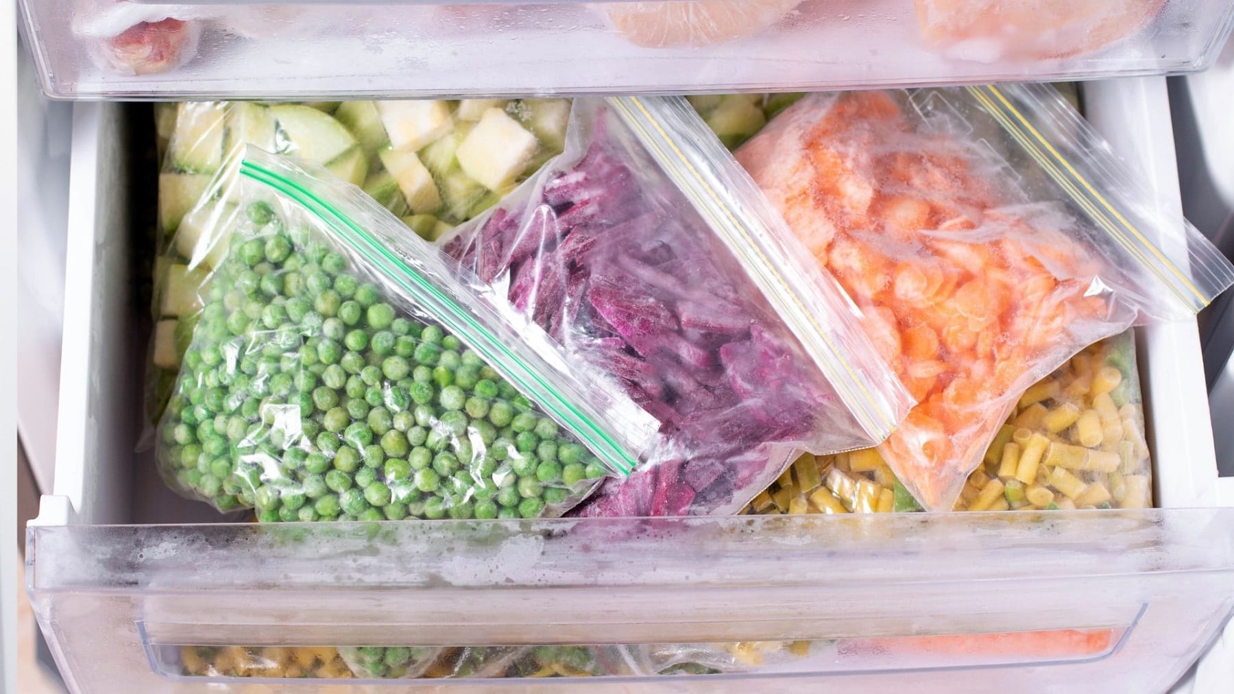 Frozen bags of peas, slice beetroot and sliced carrots, in a freezer drawer.