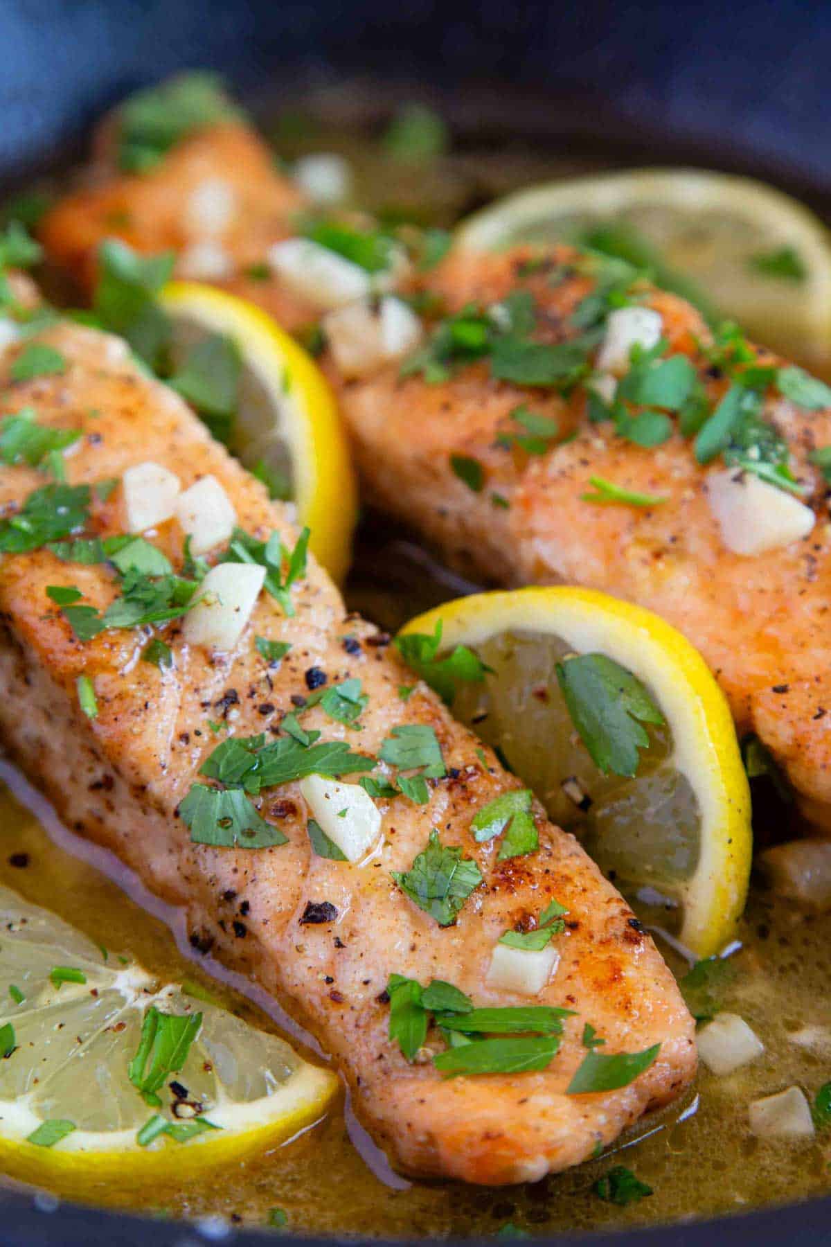freshly cooked garlic butter salmon, in a rich sauce garnished with fresh lemon and chopped parsley