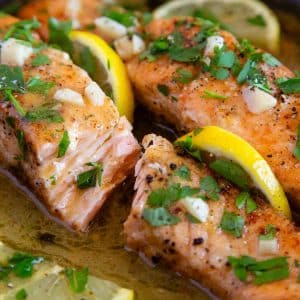 freshly cooked garlic butter salmon, in a rich sauce garnished with fresh lemon and chopped parsley