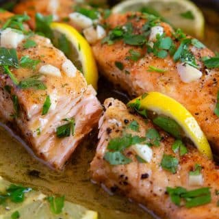 freshly cooked garlic butter salmon, in a rich sauce garnished with fresh lemon and chopped parsley