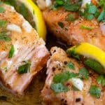 freshly cooked garlic butter salmon, in a rich sauce garnished with fresh lemon and chopped parsley