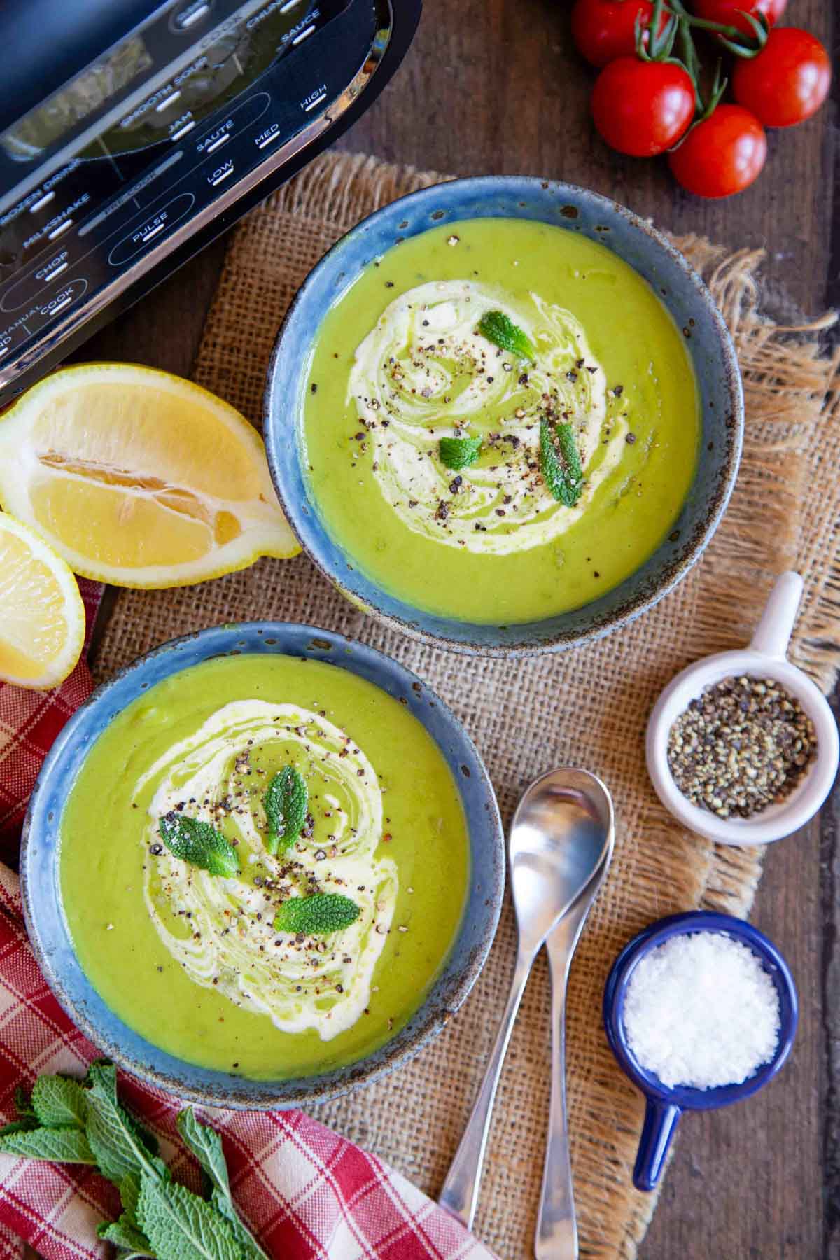 two bowls of freshly made pea soup garnished with a swirl of cream and fresh mint