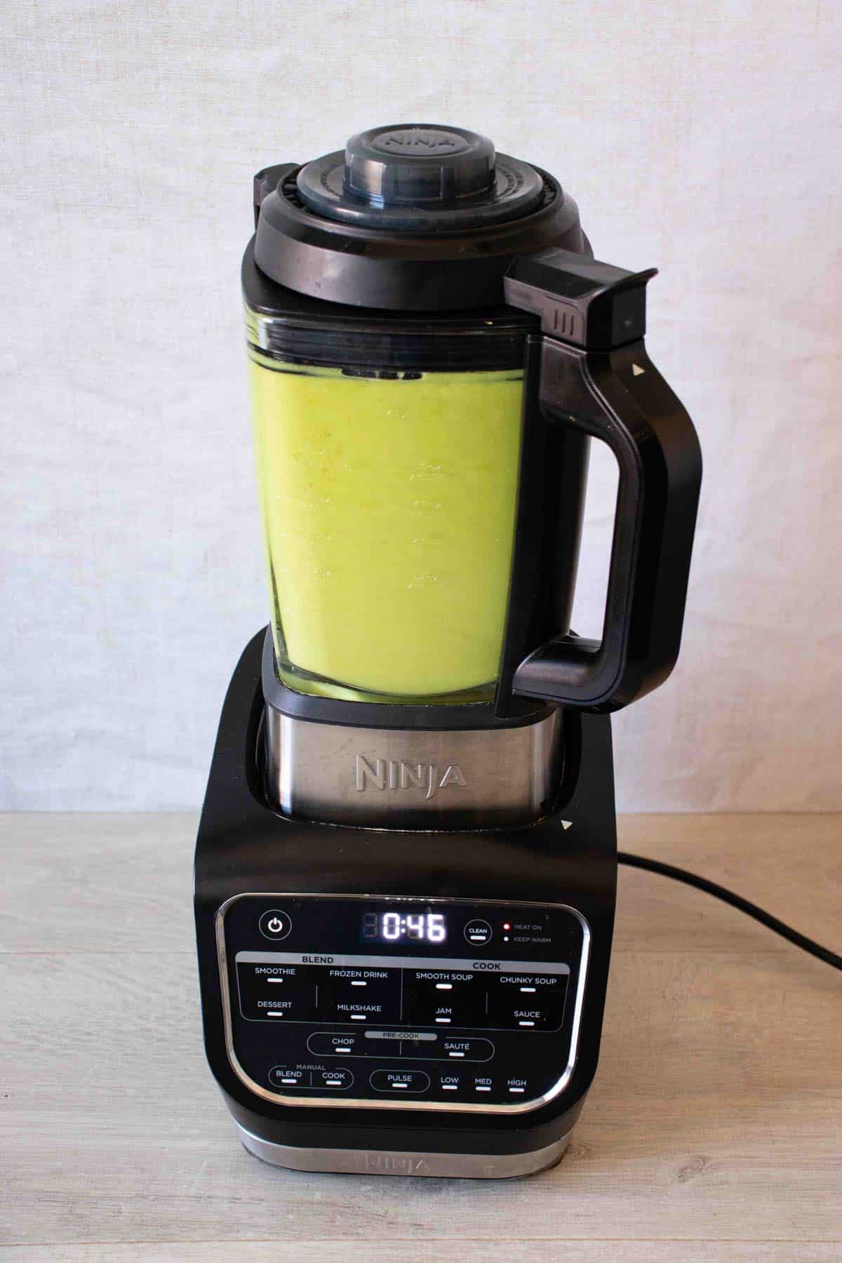 the final blend of the bright green soup in the machine