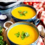 two bowls of golden mixed vegetable soup garnished with parsley