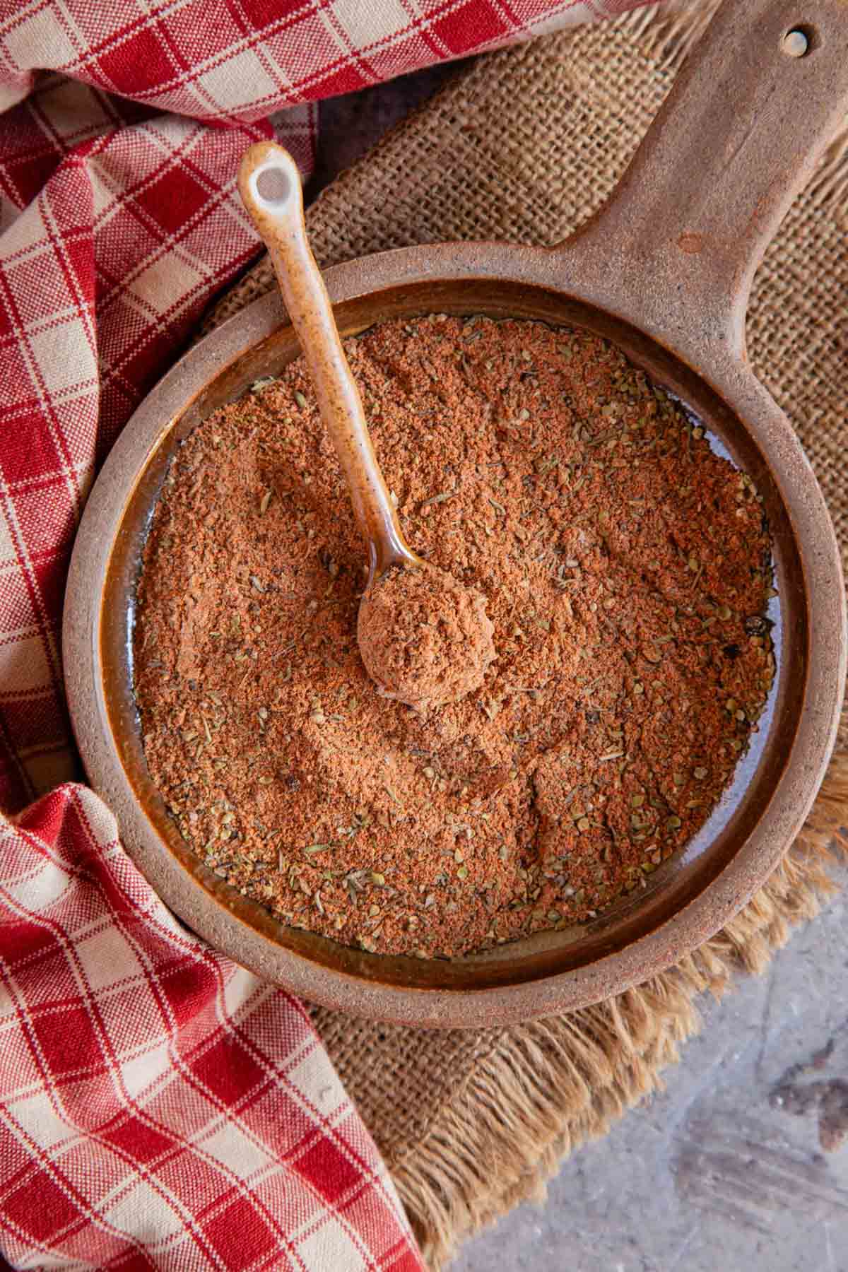 Cajun seasoning in a round earthenware dish with a pottery spoon ready to use