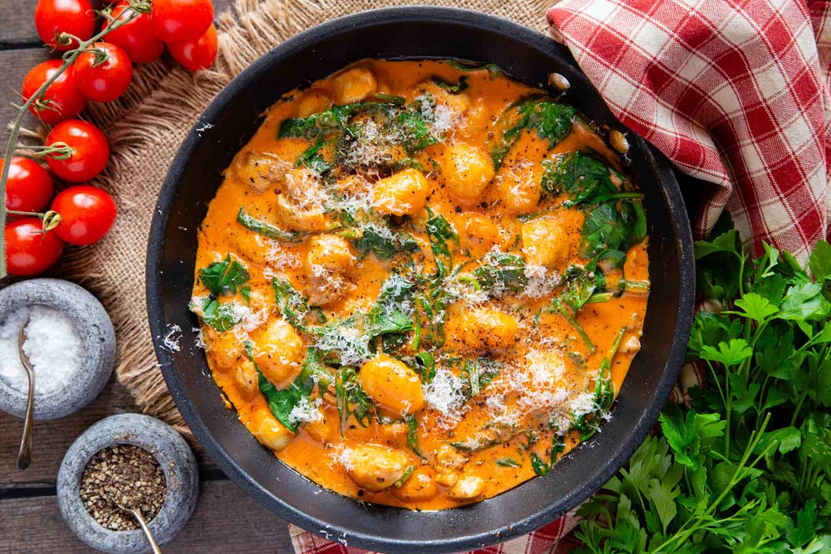 From above the bright orange sauce contrasts with the green of the spinach and creamy white of grated cheese