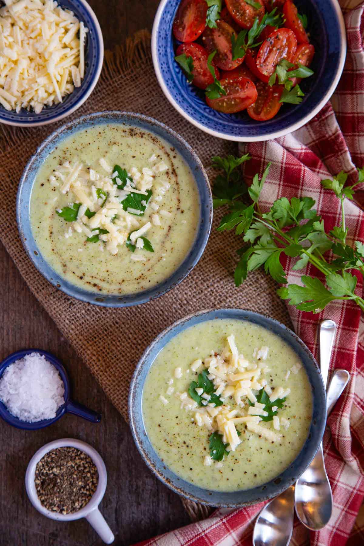 two bowls of soup garnished with grated cheddar and parsley leaves