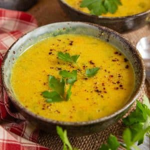 Close up of red lentil soup in a rustic pottery bowl