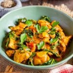 Bright orange chicken saag contrasting with green spinach and parsley garnish