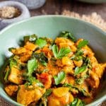 A bowl of chicken saag garnished with fresh parsley leaves