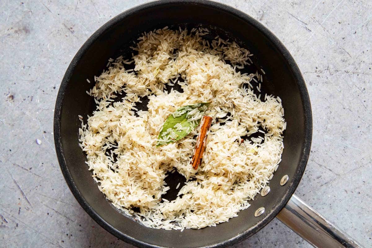 The rice is fried in the oil butter and spices before the stock is added