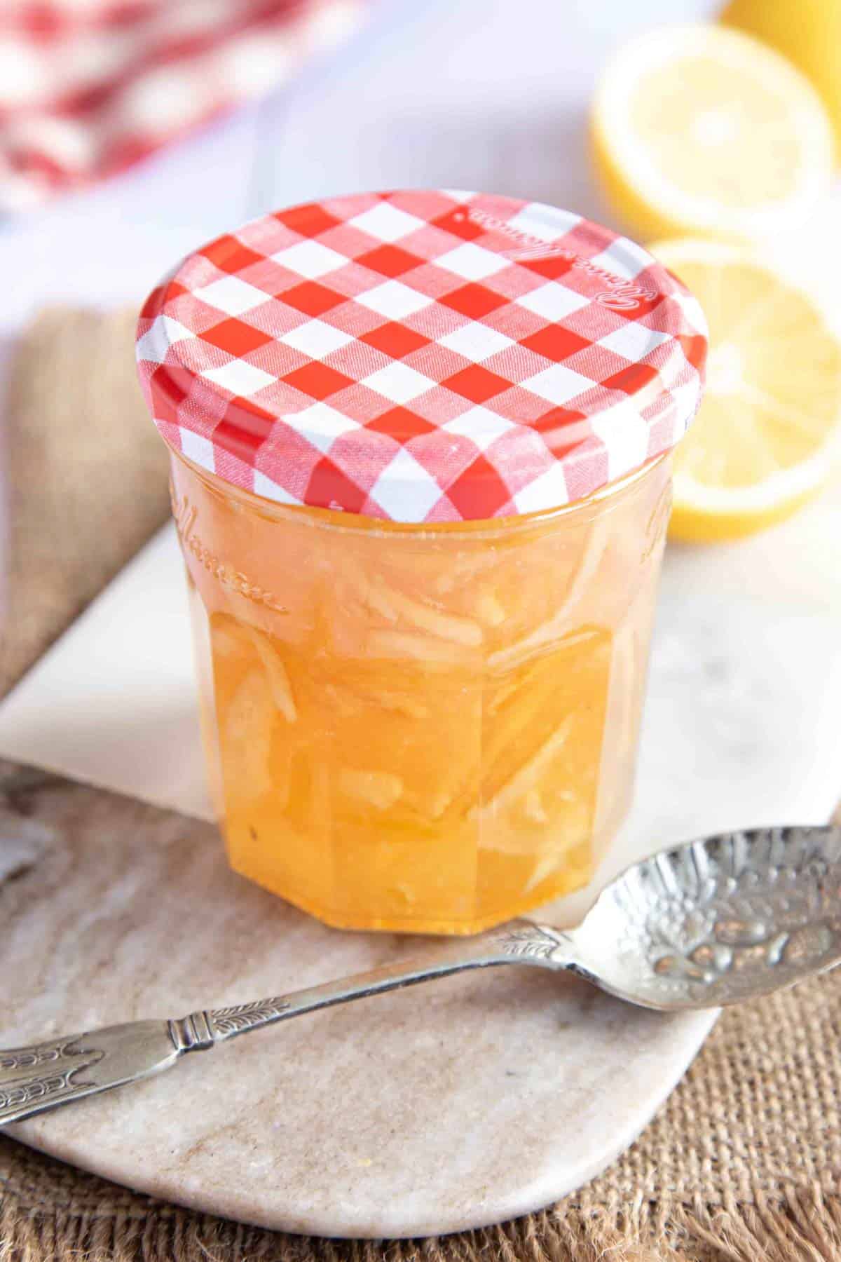 A jar of lemon marmalade sitting on a marble board