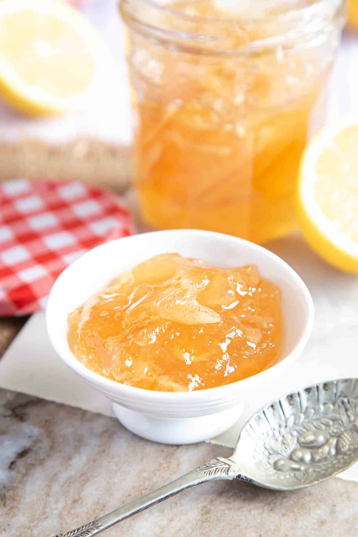 A small bowl of lemon marmalade with a spoon in the foreground