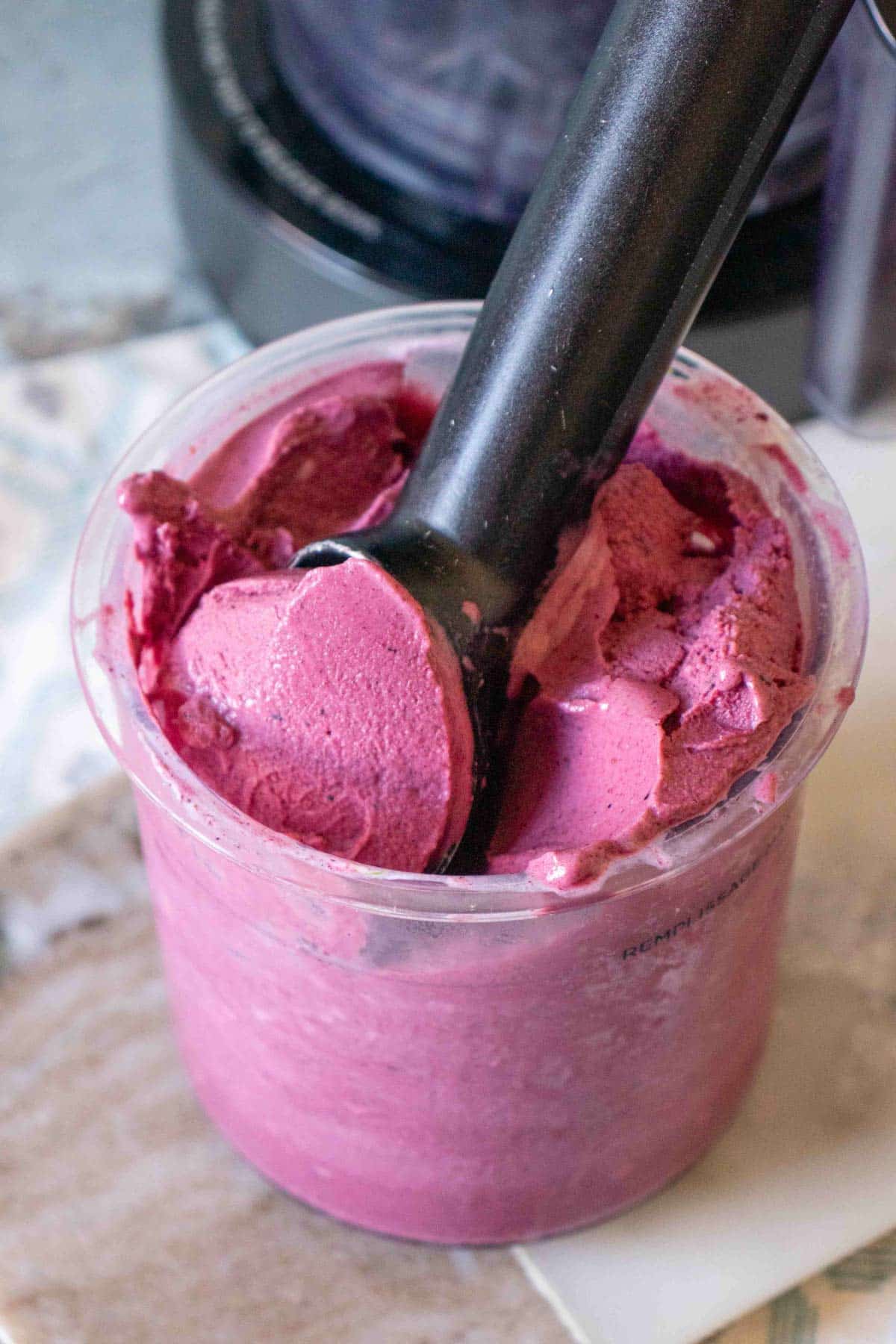 Blueberry frozen yoghurt being scooped from the Ninja Creami pot with an ice cream scoop