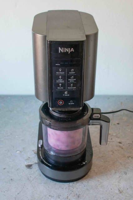 Ninja Creami machine processing a pot of pink blueberry yoghurt
