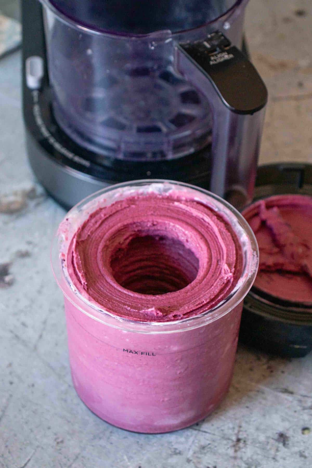 Ninja Creami pot of just processed blueberry froyo showing the large hole in the middle from the blades