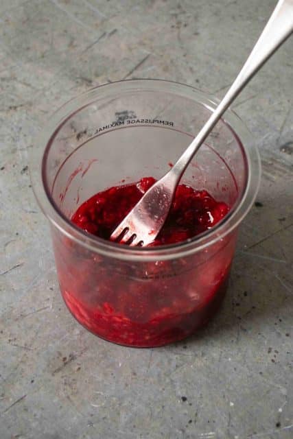 Mashing up the raspberries into a puree to make mixing easier