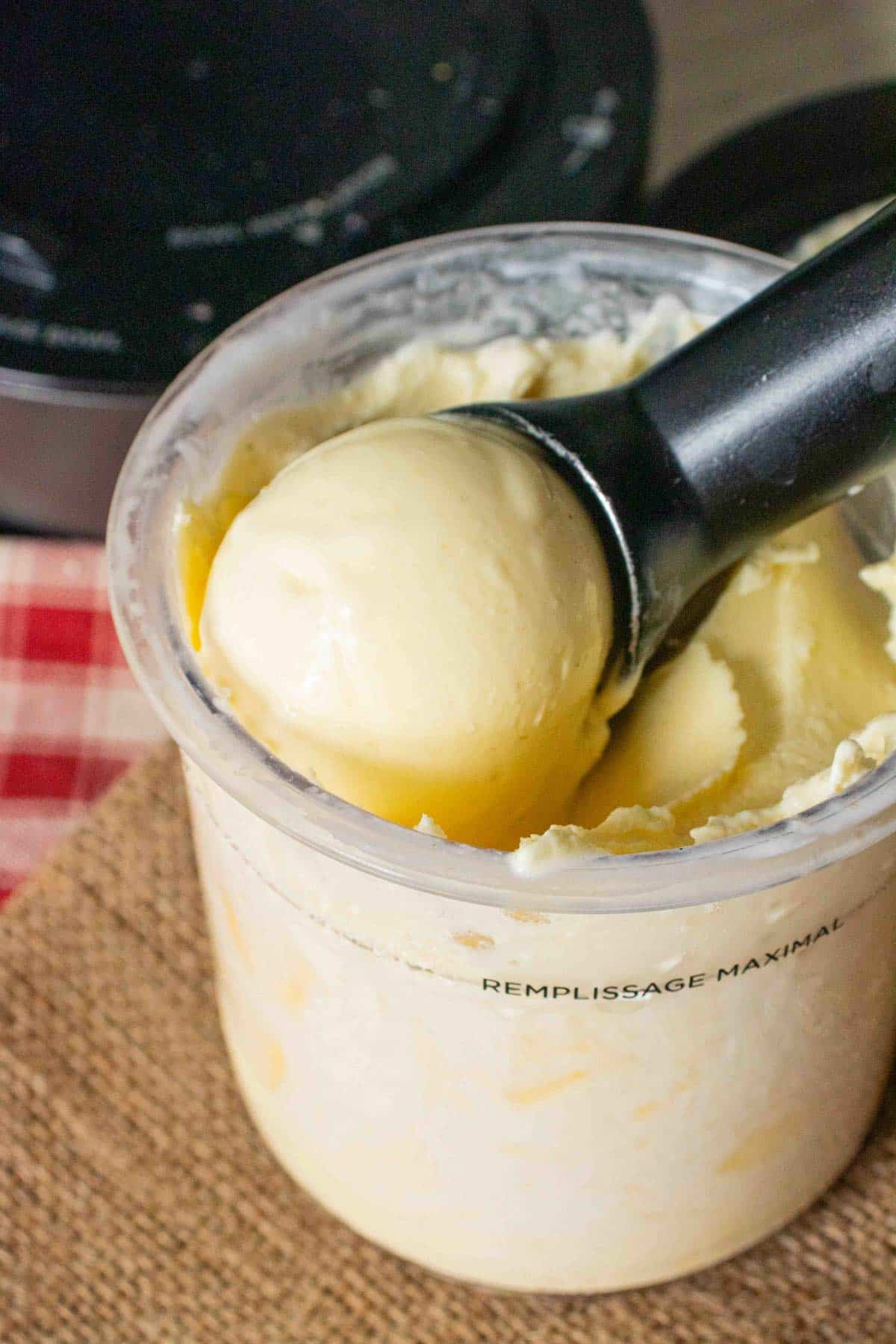 A scoop of pale yellow mango frozen yogurt being taken from the Ninja Creami pot