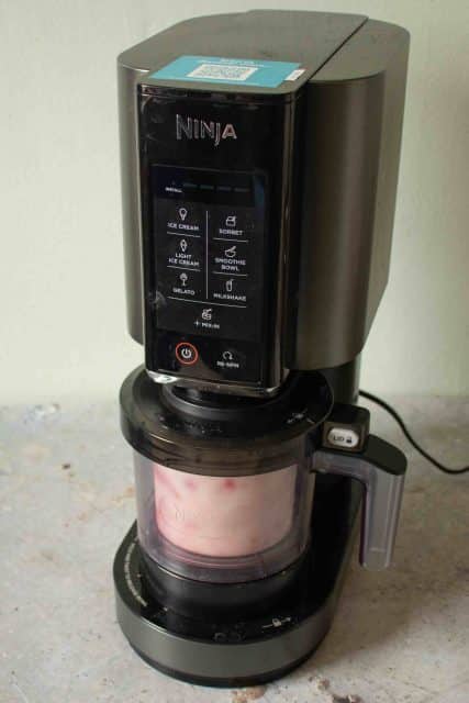 The Ninja Creami machine with a pot of strawberry ice cream ready for processing