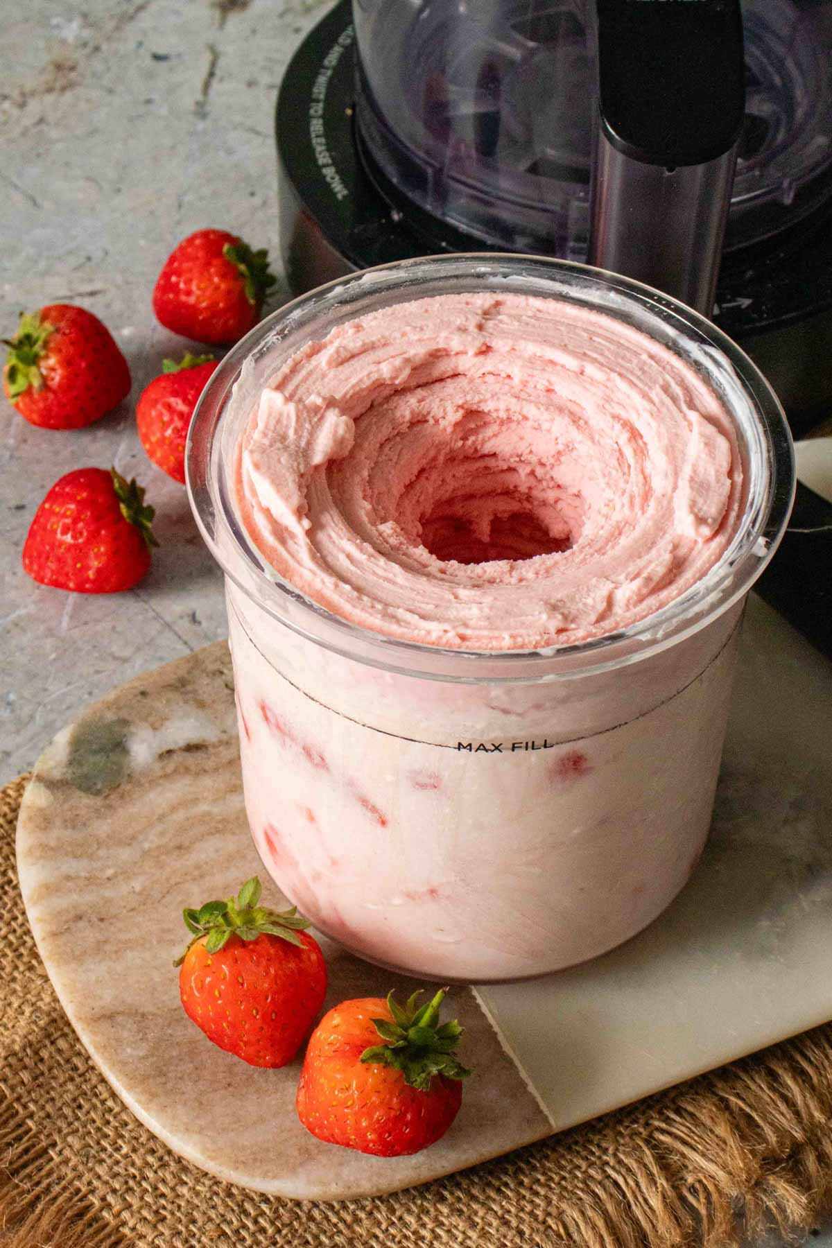 Ninja Creami pot with strawberry frozen yoghurt immediately after spinning showing the cavity in the middle of the pot