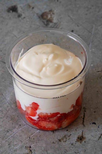 The Ninja Creami pot topped up to the max fill line with yoghurt all ready to be mixed together