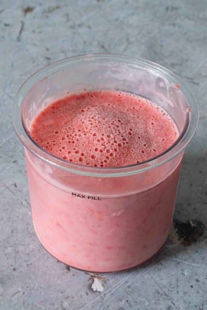 Frozen strawberry ice cream in the Ninja Creami pot ready to be processed