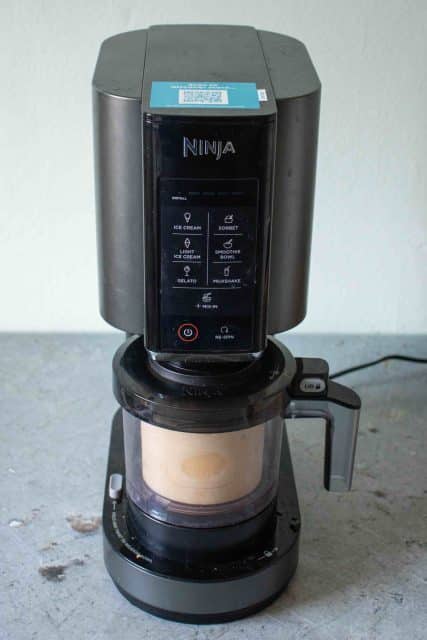 Ninja Creami machine with mango ice cream ready to process