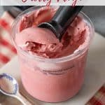 A Ninja Creami pot full of pale pink frozen yogurt with a scoop being taken