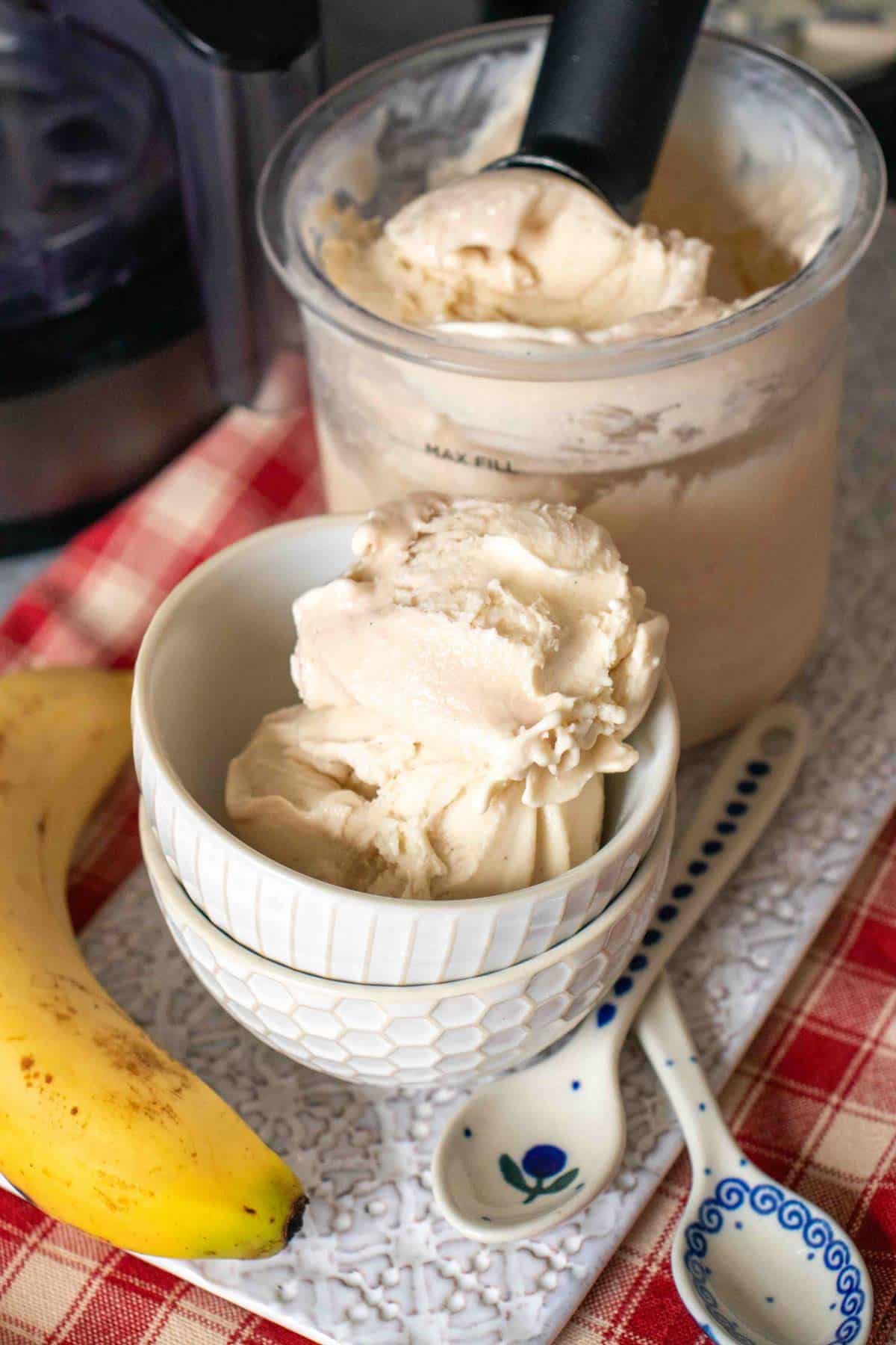 A scoop of banana ice cream in a small bowl with more ready for serving in the background
