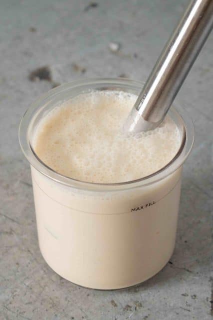 Blending the banana ice cream mixture in the Ninja Creami pot using a stick blender