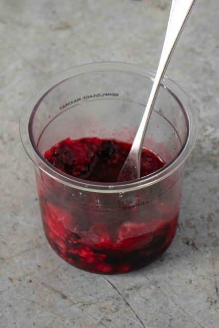 Mashed mixed fruit in the Ninja Creami pot with a fork