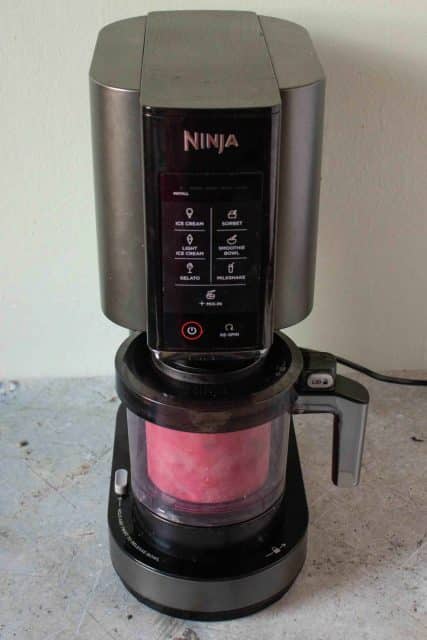 The pink frozen yoghurt is being processed in the Ninja Creami machine