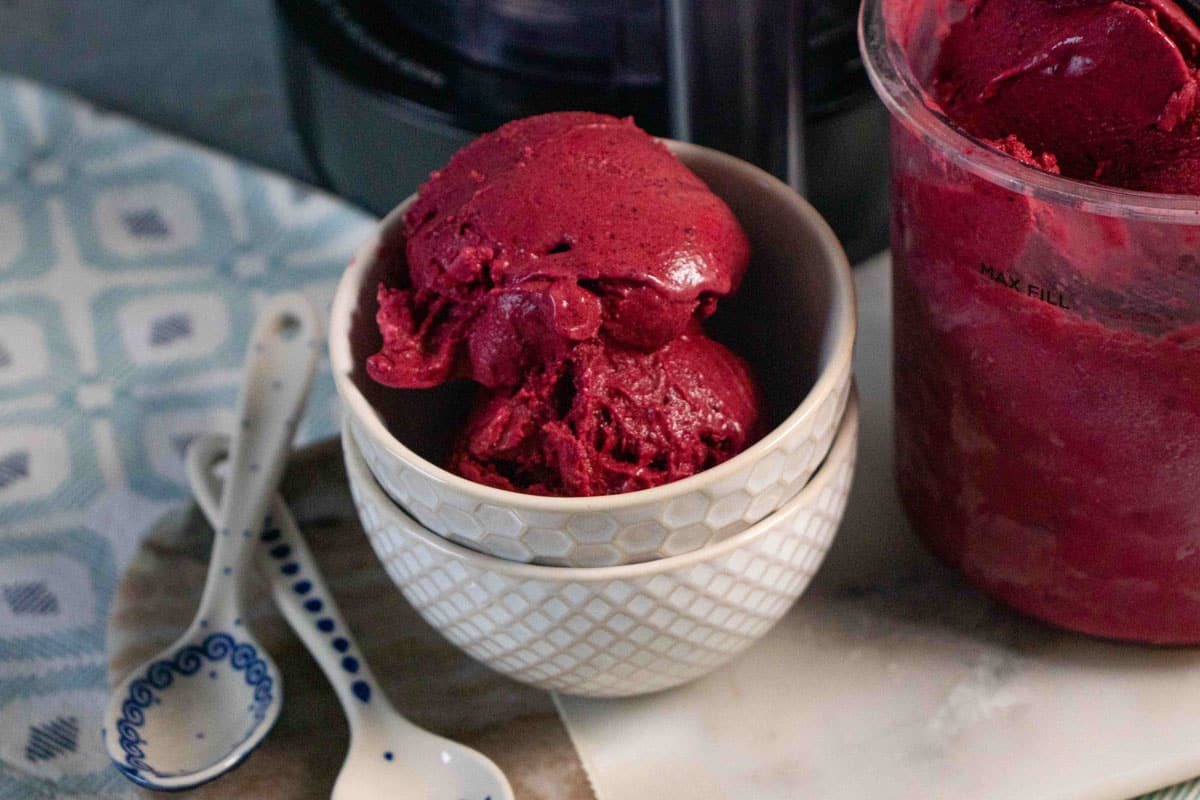 The rich dark red blackcurrant ice cream is ready to be enjoyed from a small ceramic bowl