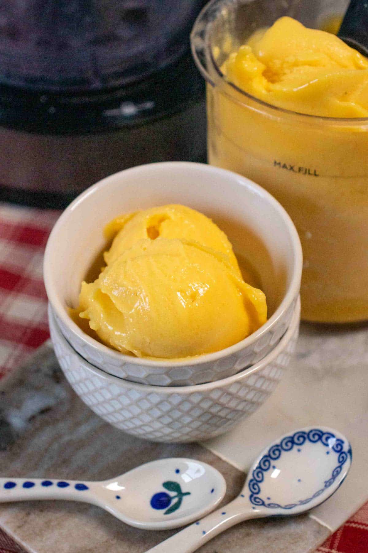 Rich golden yellow delicious mango sorbet scoops served in a white china bowl