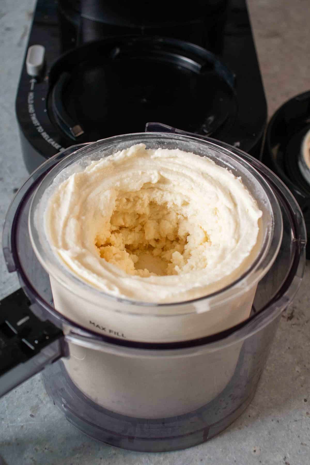Pale vanilla ice cream in the Ninja Creami pot after processing with a hole in the middle