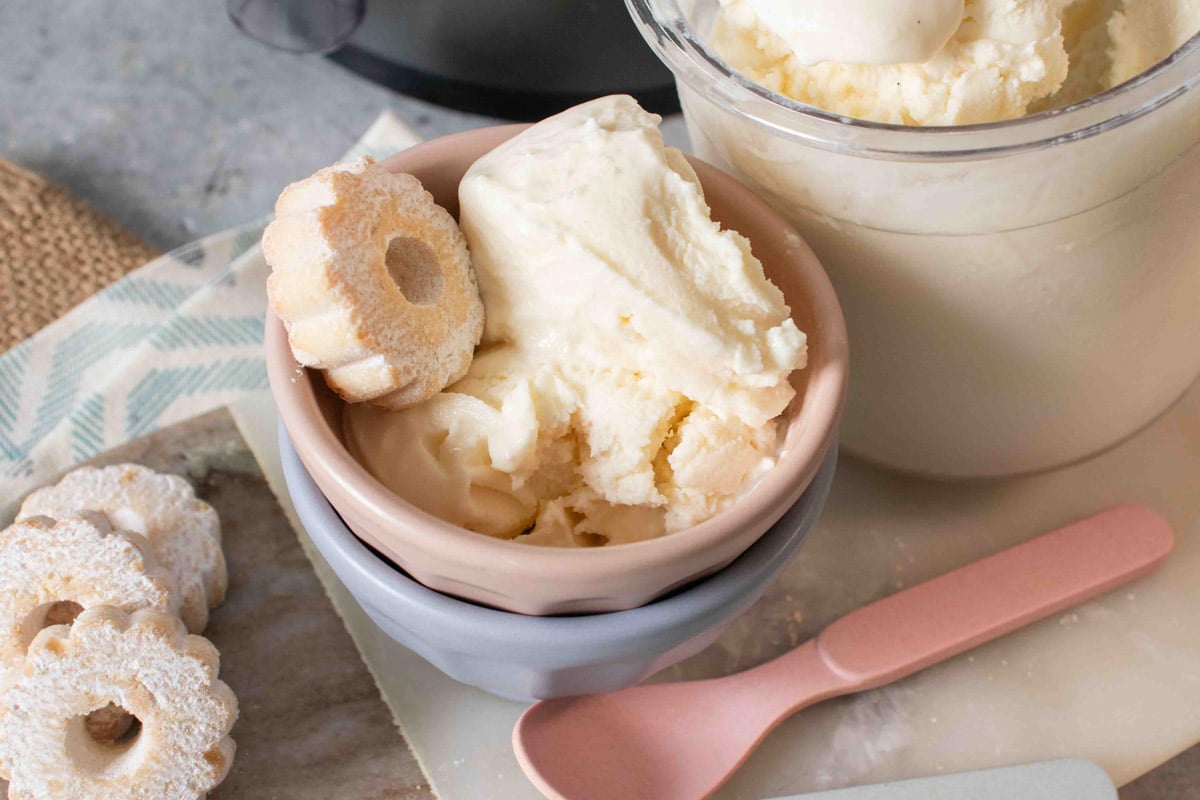 Pale cream vanilla ice cream served with a little shortbread biscuit next to a Ninja Creami pot