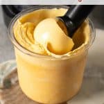 Pale yellow passionfruit froyo in the ninja creami pot with an ice cream scoop