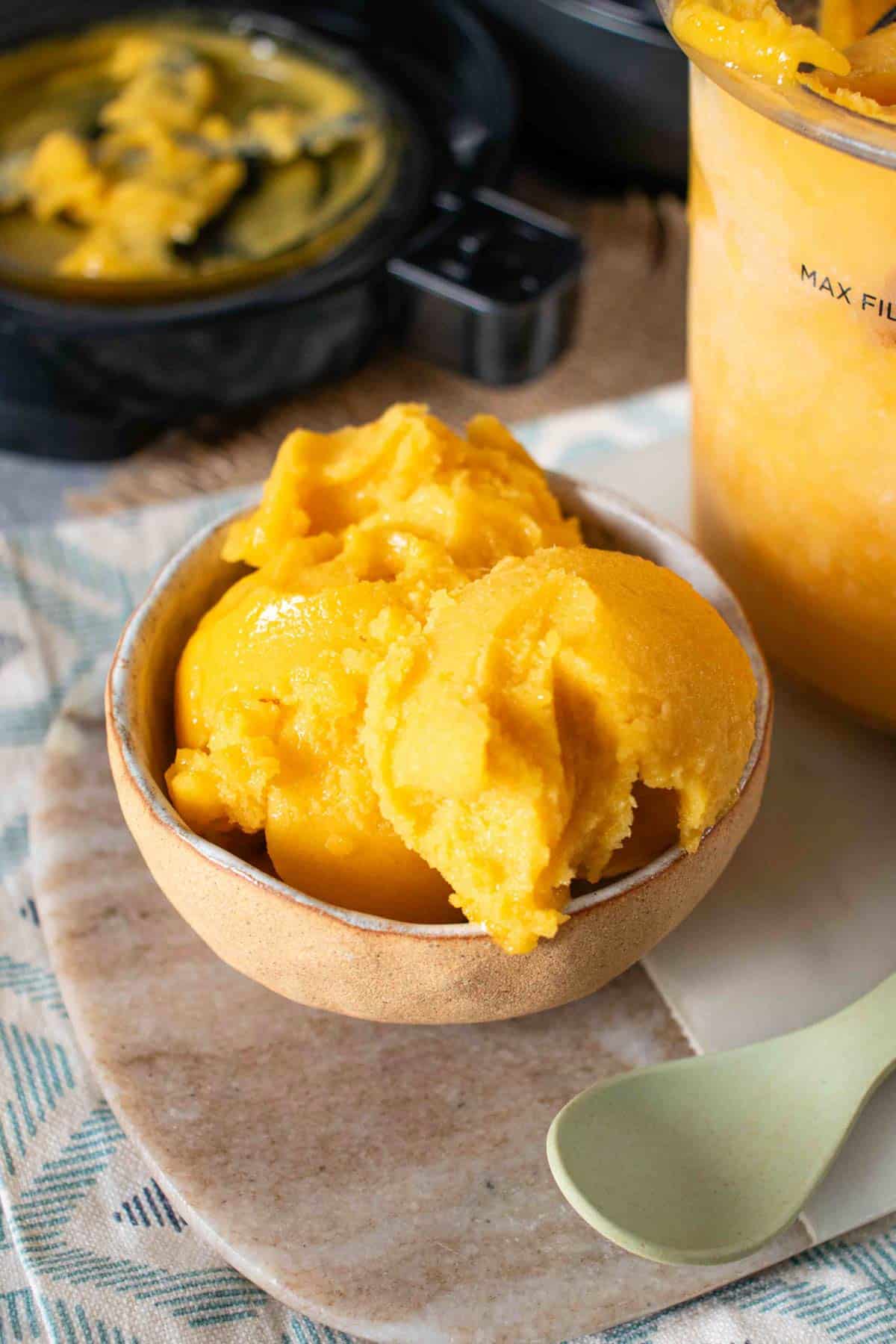 Two scoops of golden passion fruit sorbet in a small rustic bowl